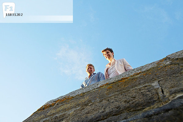 Männer schauen über den Rand der Steinmauer