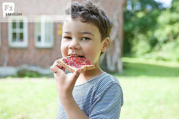 Junge isst Brot mit Marmelade im Freien