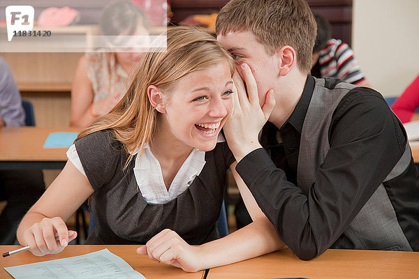 Zwei Schüler teilen ein Geheimnis im Unterricht