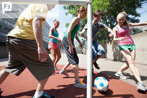 Freunde spielen Fußball auf der Straße in der Stadt