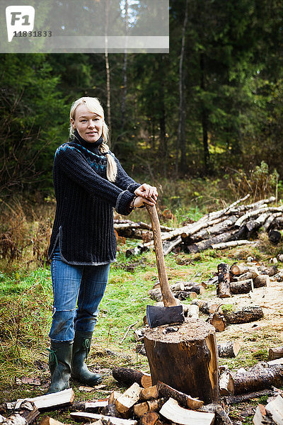 Frau hackt Brennholz im Wald