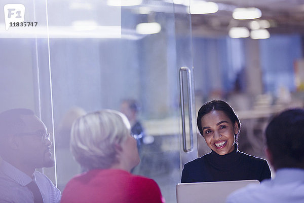 Lächelnde Geschäftsfrau mit Laptop in Konferenzraumbesprechung