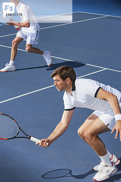 Entschlossener junger Tennisspieler mit Tennisschlägern auf dem Tennisplatz