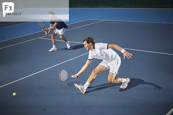 Junge männliche Tennisspieler  die Tennis spielen und mit dem Tennisschläger auf dem blauen Tennisplatz greifen.