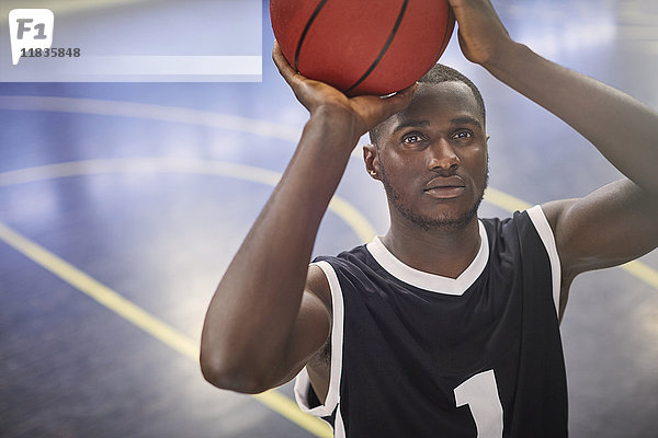 Fokussierter junger Basketballspieler  der den Ball auf dem Platz schießt.