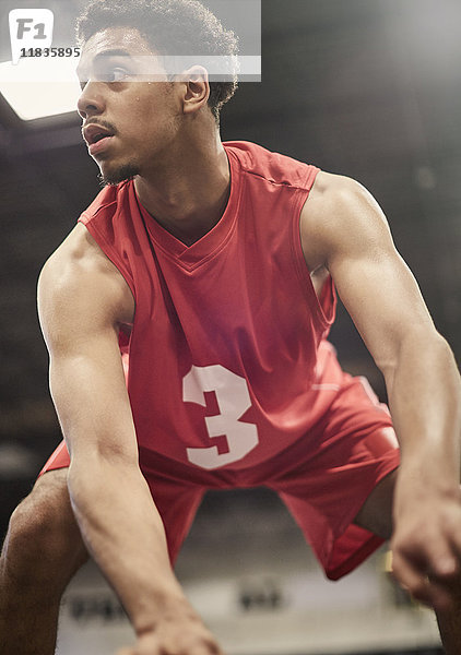 Entschlossener junger Basketballspieler  der den Ball dribbelt.