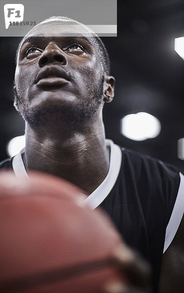 Nahaufnahme fokussierter junger Basketballspieler mit Basketball-Aufblick