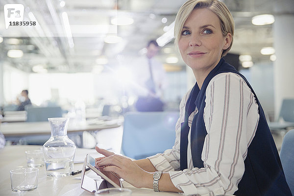 Lächelnde  selbstbewusste Geschäftsfrau mit digitalem Tablett im Büromeeting