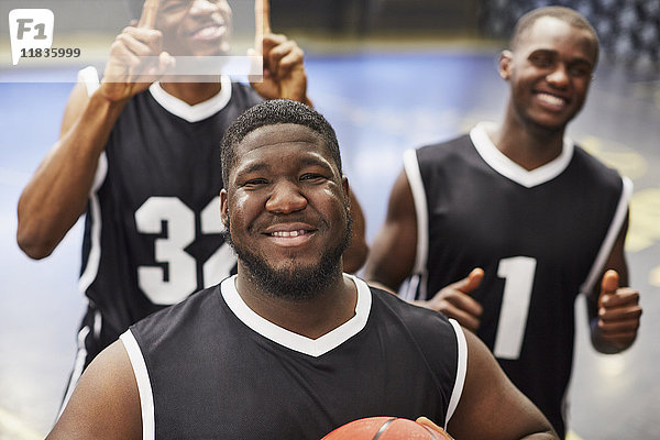 Portrait lächelndes  selbstbewusstes junges Basketballer-Team in schwarzen Trikots  das den Sieg feiert.