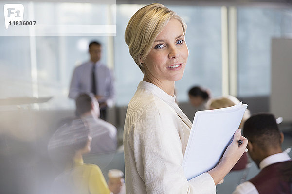 Portrait lächelnde Geschäftsfrau mit Papierkram im Konferenzraum Meeting