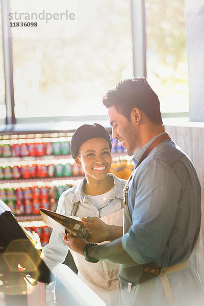 Lächelnde und sprechende Angestellte an der Kasse eines Lebensmittelmarktes