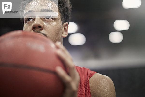 Nahaufnahme fokussierter junger Basketballspieler  der Basketball hält.