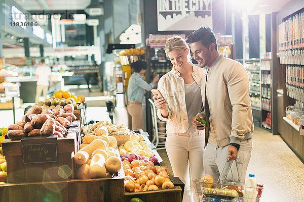 Junges Paar mit Handy beim Einkaufen im Supermarkt