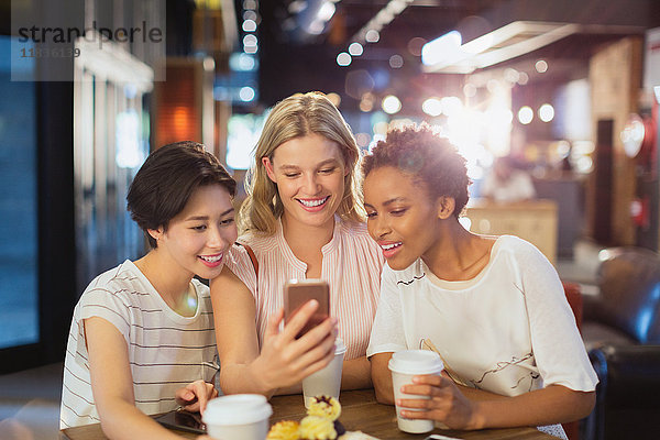 Junge Frauen  die ein Handy benutzen und Kaffee in einem Café trinken