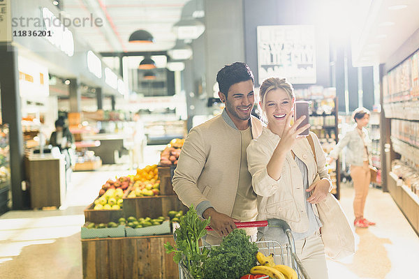 Lächelndes junges Paar nimmt Selfie in Lebensmittelgeschäft Markt