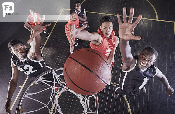 Overhead-Ansicht junge männliche Basketballspieler springen zum Rebound Basketball am Netz auf dem Basketballplatz.