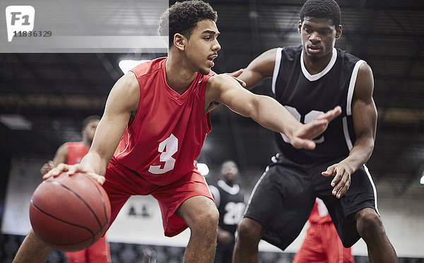 Junge männliche Basketballspieler dribbeln den Ball  Schutz vor Verteidiger in Basketball-Spiel