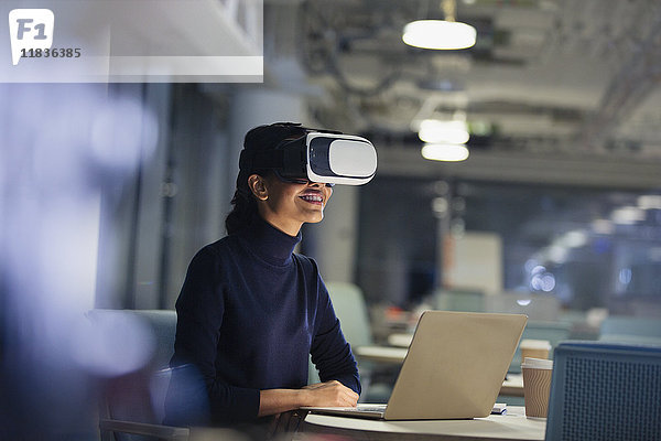 Geschäftsfrau mit Virtual-Reality-Simulator am Laptop im dunklen Büro