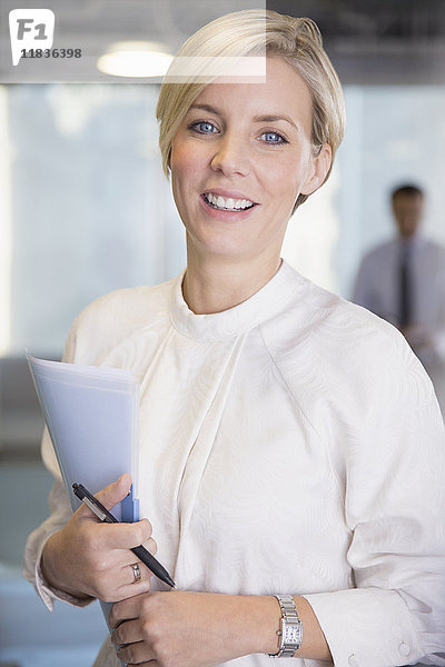 Portrait lächelnde  selbstbewusste Geschäftsfrau mit Papierkram