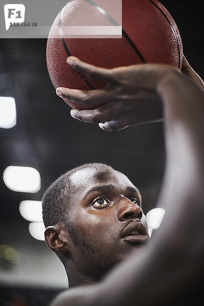Nahaufnahme fokussierter junger Basketballspieler  der den Ball schießt.