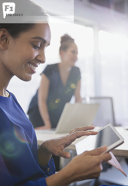 Lächelnde Geschäftsfrau mit digitalem Tablett in Konferenzraumbesprechung