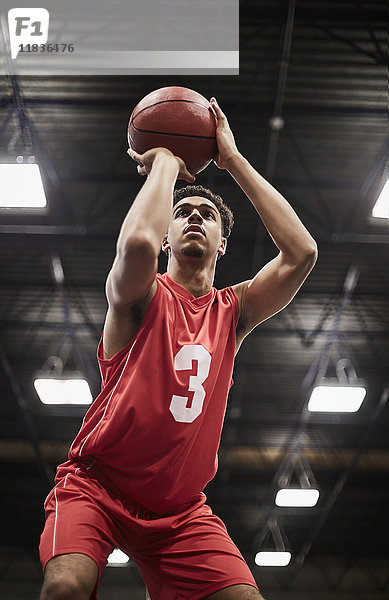 Fokussierter junger Basketballspieler beim Schießen im freien Wurf