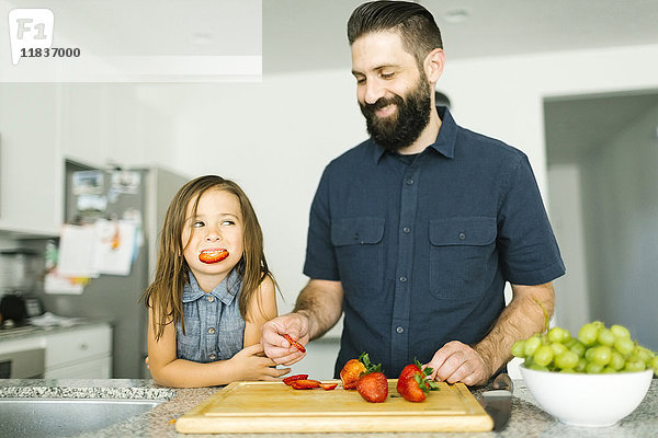 Vater mit Tochter (6-7) isst Erdbeeren