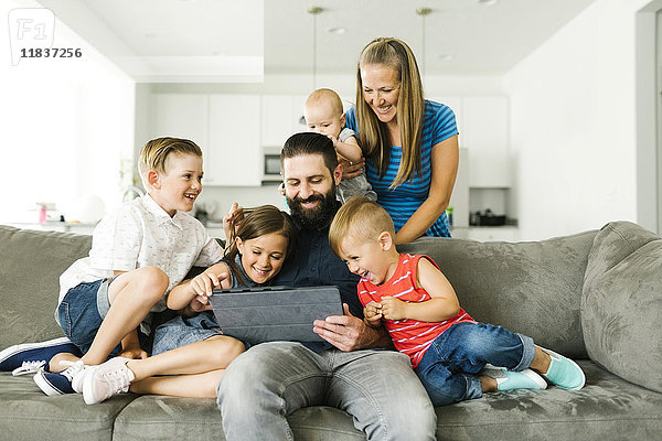 Familie mit vier Kindern (6-11 Monate  2-3  6-7)  die ein digitales Tablet benutzen