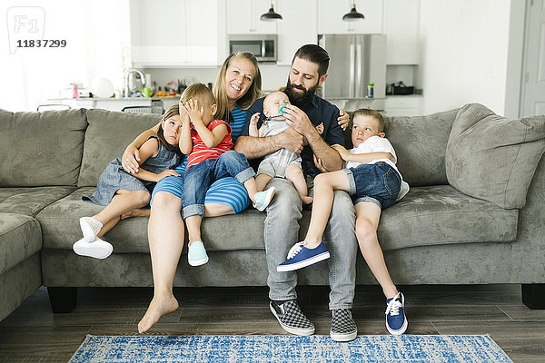 Familie mit vier Kindern (6-11 Monate  2-3  6-7) verbringt Zeit auf dem Sofa