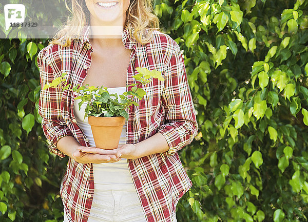 Lächelnde Frau mit Topfpflanze