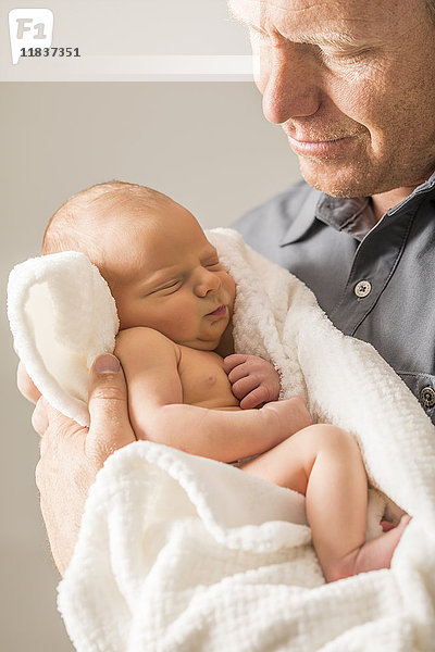 Vater umarmt neugeborenen Sohn (0-1 Monat)