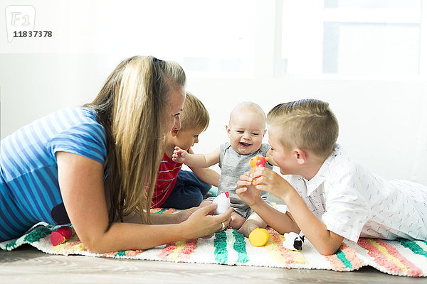 Mutter spielt mit ihren drei Kindern (6-11 Monate  2-3  6-7)