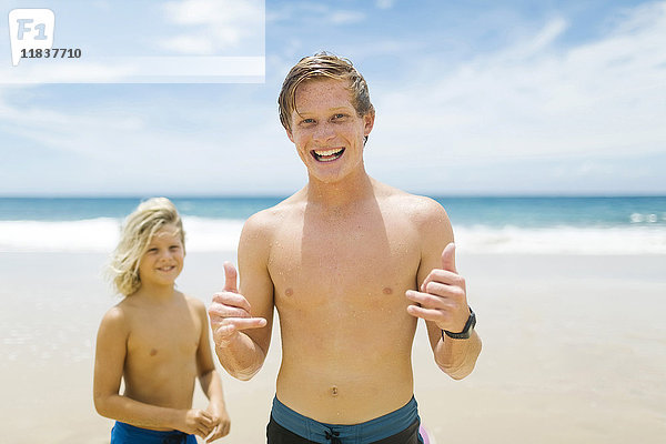 Junger Mann mit jüngerem Bruder (4-5) beim Spielen am Strand