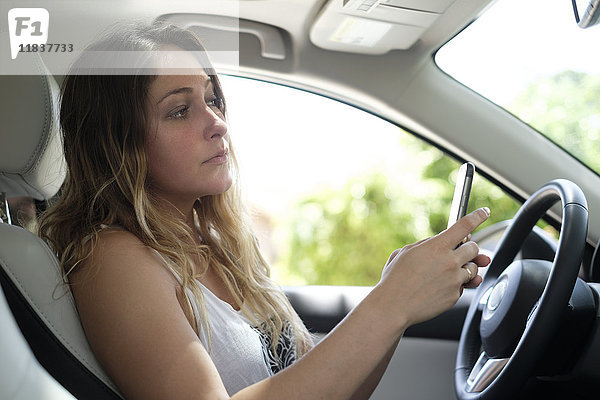 Frau benutzt Smartphone im Auto