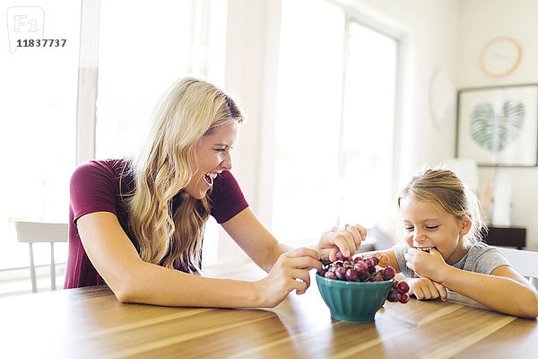 Mutter und Tochter (6-7) essen Weintrauben