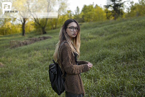 Asiatisches Teenager-Mädchen trägt Rucksack im Feld
