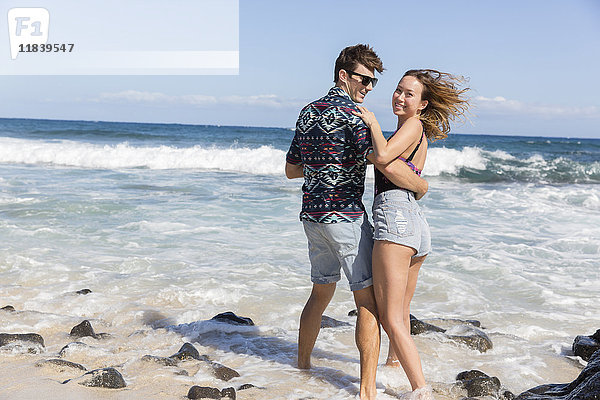 Lächelndes  sich umarmendes Paar am windigen Strand