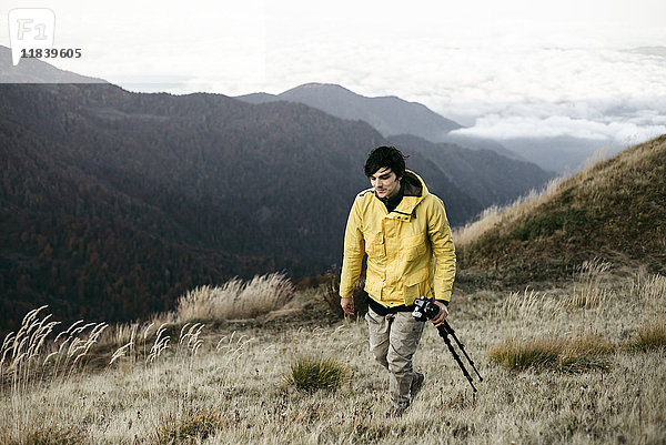 Kaukasischer Mann mit Stativ in abgelegener Berglandschaft