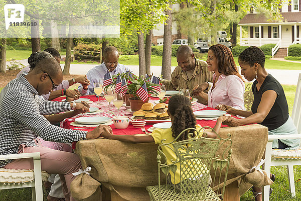 Mehrgenerationenfamilie beim Beten am Picknicktisch