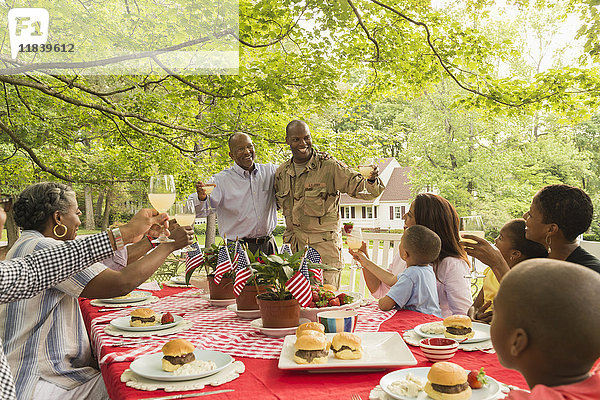 Soldat und Mehrgenerationenfamilie stoßen beim Picknick mit Limonade an