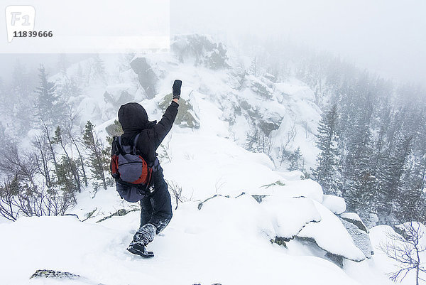 Kaukasischer Wanderer winkt auf verschneitem Berg