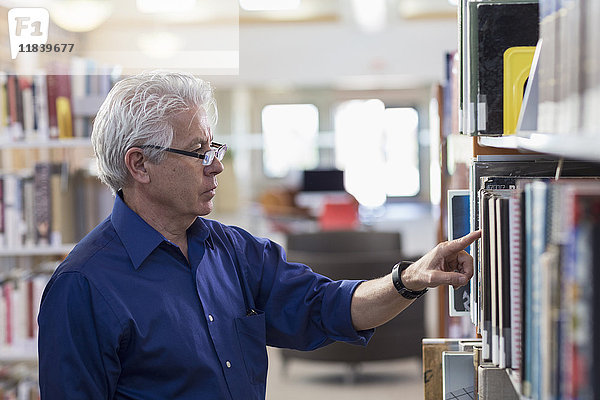 Neugieriger hispanischer Mann sucht in der Bibliothek nach einem Buch