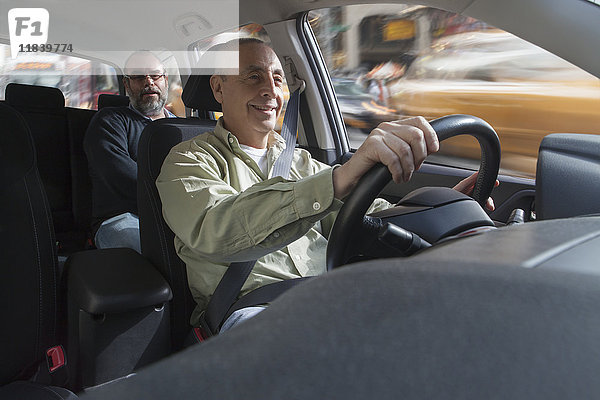 Lächelnder hispanischer Mann am Steuer eines Autos mit Beifahrer