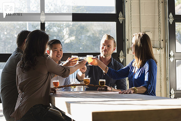 Freunde stoßen mit Bier in einer Brauereikneipe an