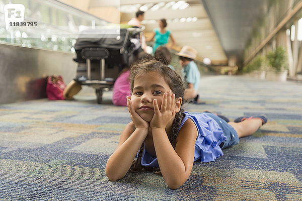 Gelangweiltes Mädchen liegt auf dem Boden eines Flughafens