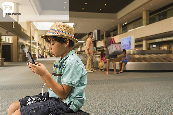 Junge spielt mit Handy im Flughafen