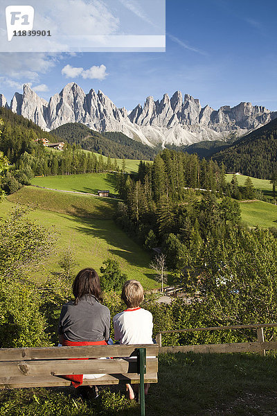 Mutter und Sohn sitzen auf einer Bank und bewundern die malerische Aussicht auf die Berge