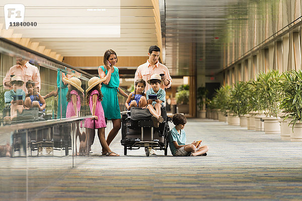 Familie wartet im Flughafen und benutzt Handys
