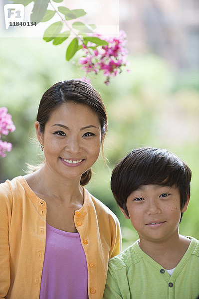 Porträt einer lächelnden asiatischen Mutter und ihres Sohnes in der Nähe von Blumen