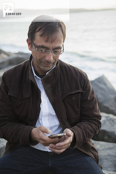 Mixed Race Mann texting auf Handy am Strand